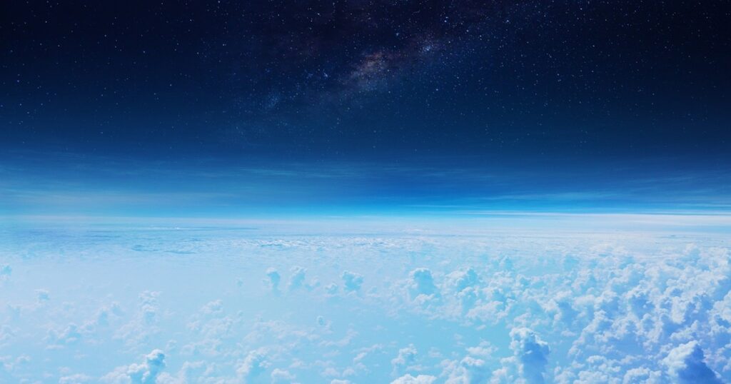 雲海の上に広がる星空と青い地平線